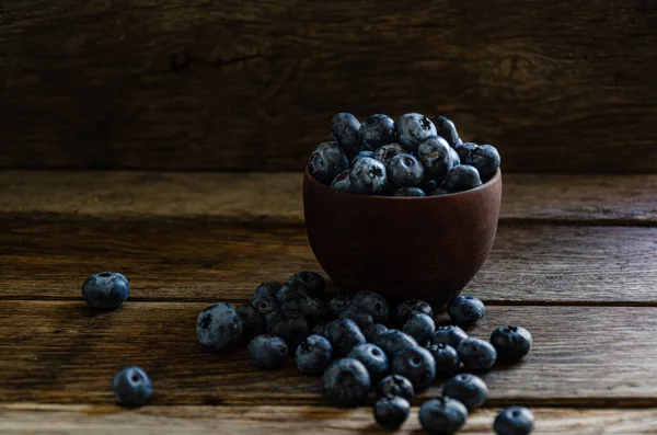 Blueberries in a wooden bowl. On a wooden table, on a wooden background.