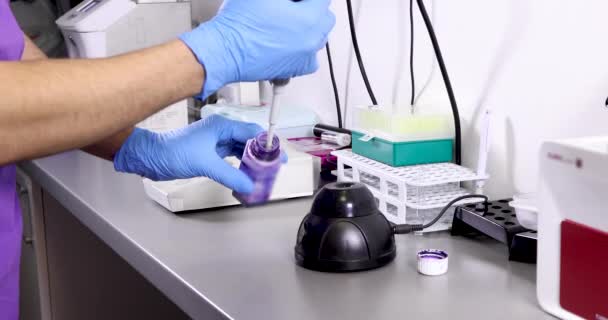 생화학자는 볼텍스와 주사기를 사용하여 실험실에서 일하고 — 비디오