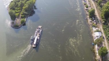Aerial shot of a ferry boat with vehicles enters the channel - green water full of algae