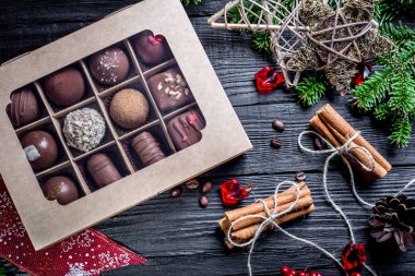 Raffaello tarzında siyah ahşap arka plan çikolatalarının kompozisyonu organik doğal ürünler, tarçın, ceviz, kaju, badem...