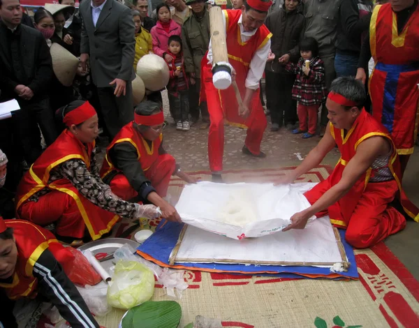 Люди в традиционных костюмах экзамен, чтобы сделать круглый липкий рисовый пирог — стоковое фото