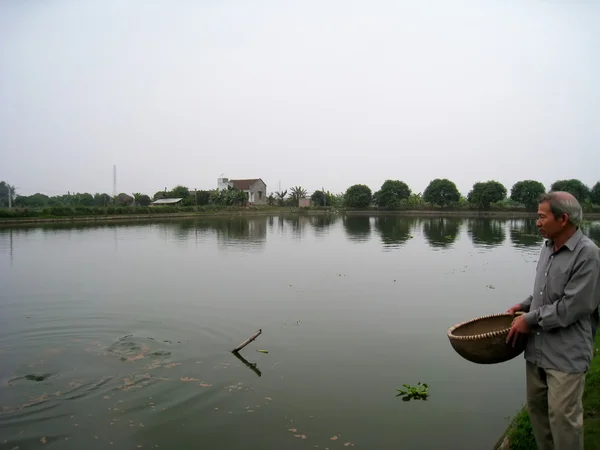 Vietnamesischer Landwirt füttert Fische — Stockfoto