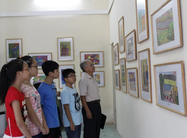 Old man and teens watch picture exhibition — Stock Photo, Image