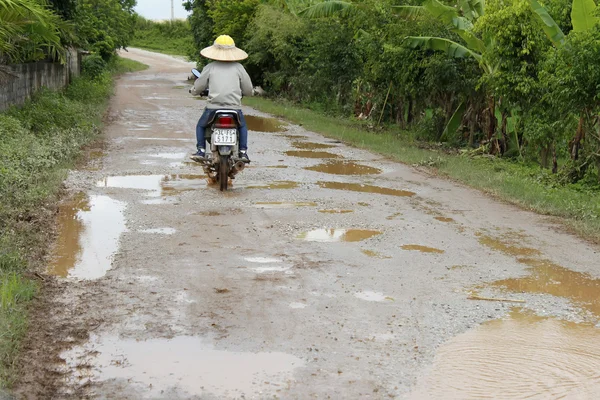 El hombre no identificado monta motocicleta en carretera fangosa — Foto de Stock