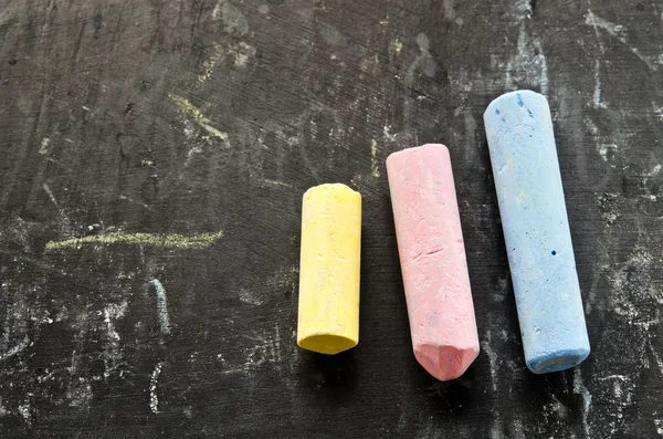 Colorful chalks on blackboard — Stock Photo, Image