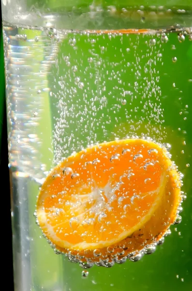 Pomarańczowy przelewanie do czystej wody — Zdjęcie stockowe