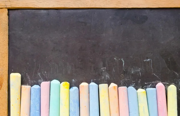 Colorful chalks on blackboard — Stock Photo, Image