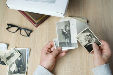 Yakın plan erkek, 1940-1950 yılları arasında çekilmiş eski vintage fotoğraflarını tutuyor. Aile ağacı, soy ağacı, çocukluk anıları, atalarımızın hafızası.