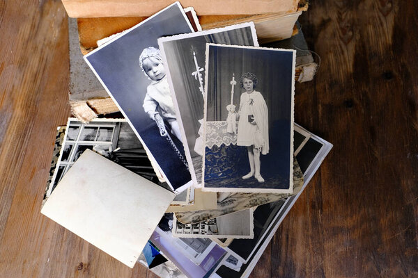 stack of vintage photos, retro photography of 1940-1950 on wooden table, old books, concept of genealogy, memory of ancestors, family tree, genealogy, childhood memories, family archive