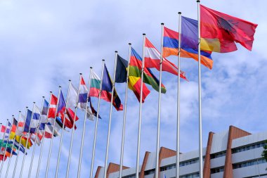Avrupa Parlamentosu, devlet sembolleri, uluslararası işbirliği konsepti, küresel iş dünyası, Avrupa Parlamentosu binası yakınlarındaki mavi gökyüzünde rüzgarda dalgalanan Avrupa ve diğer ülkelerin ulusal bayrakları