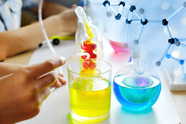 两个7 9岁的孩子 小学生 做化学实验 把彩色液体倒入玻璃瓶 混合颜色 学校教育理念 亲自动手学习化学 — 图库照片
