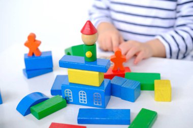 çocuk, küçük çocuk, 2 yaşındaki kız renkli ahşap figürlerden kuleler ve binalar inşa ediyor, konut inşaatı, ipotek, sigorta, mutlu çocukluk, çocuk oyunları