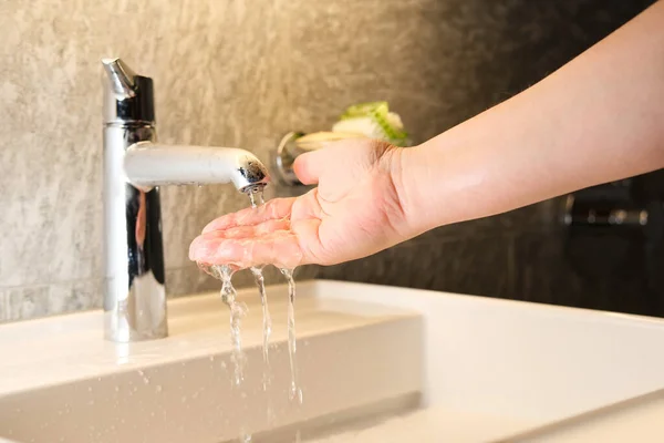水从镀铬水龙头中倒入一条细细的溪流 女孩洗手 健康的生活方式 — 图库照片