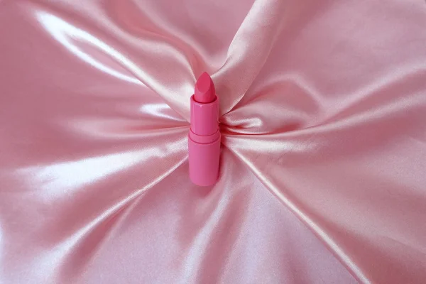 繊細なピンクの背景にマットな口紅 ピンクのシルク生地 クローズアップ 装飾化粧品 リップケア 女性の美しさの概念 — ストック写真