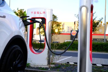 FRANKFURT, Almanya - Eylül 2021: Beyaz Tesla Model Y elektrikli yolcu arabası şarj istasyonunda pil dolduruyor, alternatif enerji geliştirme kavramı, elektrikli araç üretimi