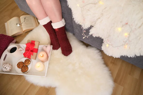 赤い靴下の女性の足を閉じます ホットドリンク付きの白いトレイ キャンドル お菓子 ギフト付きのボックス 居心地の良い家のコンセプト 良い気分 豪華なライフスタイル 誕生日 — ストック写真