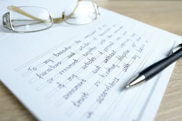 close-up of glasses and a ballpoint pen on paper with a written will, the concept of a legal order on her movable and immovable property in the event of a person\'s death for the heirs