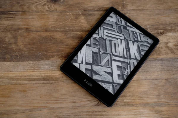 Modern siyah e-kitap okuyucu, dijital kitap Kindle, eski ahşap masa üzerinde elektronik olarak metin görüntülemek için tablet bilgisayar aygıtı, elektronik kağıt teknolojisi, kurgu okuma kavramı, metin düzenleme