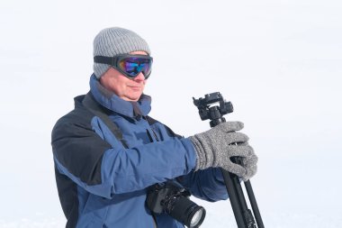 Kameralı yaşlı bir adam, dağ yürüyüşçüsü kış manzarasına hayran, spor konsepti, sağlıklı yaşam tarzı, kış etkinliği, güzel kış doğal manzarası, kışın beyaz ormanda yürüyor.