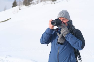 Kameralı yaşlı bir adam, dağ yürüyüşçüsü kış manzarasına hayran, spor konsepti, sağlıklı yaşam tarzı, kış etkinliği, güzel kış doğal manzarası, kışın beyaz ormanda yürüyor.