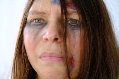 Kadın gözyaşı lekeli yüzünün yakın çekimi, yara bere ve sıyrıklarla dövülmüş bir kadın, sessiz bir yardım çığlığı, aile içi şiddet konsepti, acı çekme duygusu, adam kaçırma, tehlike altında olma.