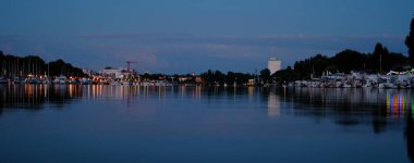 Güzel deniz, Almanya 'daki Wiesbaden rıhtımında tekneleri ve yatları olan nehir manzarası, sudaki akşam ışıkları ve yansımaları, su yolculuğu konsepti, su sporları.