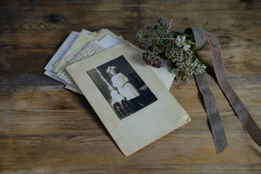 Doğal ahşap masa üzerinde 50-60 'lı yılların eski monokrom fotoğrafları, çocuğun fotoğrafı, kurumuş çiçekler, aile ağacı konsepti, soy ağacı, atalarla bağlantı, gençlik anıları, çocukluk anıları.