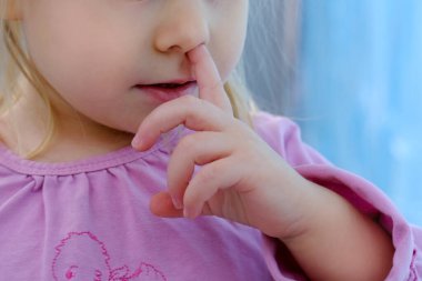 Yüzün alt kısmının yakın plan çekimi, küçük çocuk, 2 yaşında sarışın bir kız parmaklarını burunlarına soktu, çocukluk kavramı, daha önceki çocuk eğitimi, kötü alışkanlıklar