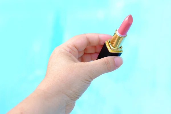 新しいピンク 青の背景に桃の口紅とチューブを保持するクローズアップ女性の手は 化粧をしたい 装飾的な化粧品の概念 — ストック写真