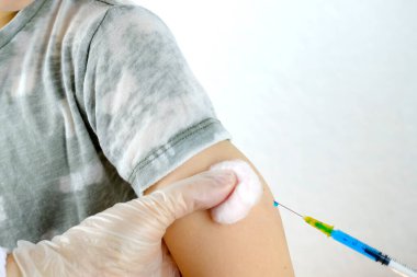 Çocuğun eli yakın, doktorun elinde şırınga, eldivenli hemşire 8-10 yaşındaki çocuğa iğne yapıyor, tıbbi konsept, Coronavirus covid-19 virüsüne karşı aşı