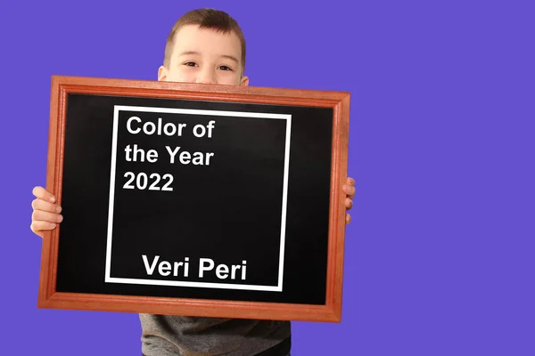 快乐的男孩手里拿着一个黑色的黑板 上面刻着 淡紫色的背景 2022年的Veri Peri Pantone色彩的概念 时尚色彩的趋势 — 图库照片