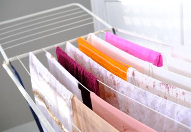 Islak çamaşırların bir tel oda kurutucusuna asılıp kurutulması, ev işleri konsepti, sığ alan derinliğinde seçici odaklanma
