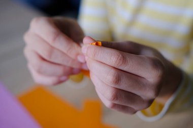 Renkli kağıdın yakın çekimi, uygulamalar için materyal, çocukların elleri origami tekniğini renkli kağıtlardan, dikiş tekniğinden, el yapımı kavramından ve yaratıcılıktan katlıyor.