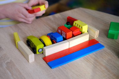 Çocukların ellerinde renkli tahta küpler, dominolar, çocuk 7-9 yaşları ev yapar, araba yuvarlar, inşaat konsepti, yaratıcılığın gelişimi, motor becerileri, sabır.