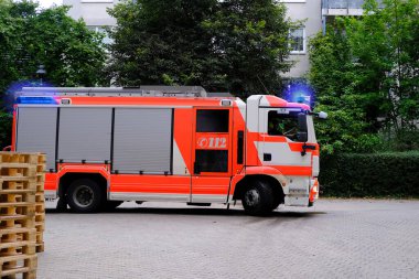 Çok katlı bir binanın avlusuna kırmızı itfaiye aracı geldi. Acil durum 112. Almanya 'da yangın kavramı, yanıp sönen ışıklar.