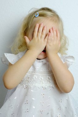 Küçük çocuk, sarışın kız 2 yaşında beyaz elbiseli, elleri dargınlıktan, çocukların kaprislerinden, aile içi şiddetten, psikolojik şiddetten, zor çocukluktan gözlerini kapattı.