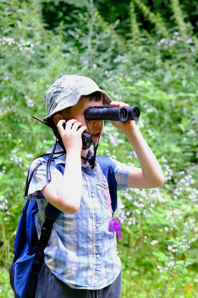 8年の子供 パナマの帽子の少年 手でウォーキートーキーとシャツをプレイした森の中に立って 双眼鏡 オリエンテーリング 野生での生存のハイキングの概念を注意深く見てください — ストック写真