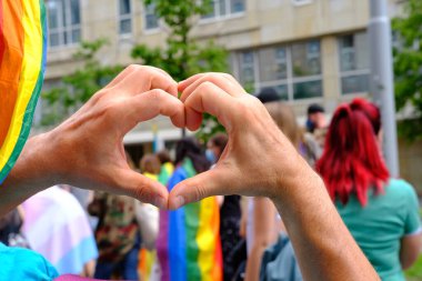 LGBTq hareketinin üyeleri, gökkuşağı bayraklarıyla şehirde eşcinsel gururu geçit töreni, insanların gösterisi, lezbiyen, gey, biseksüel, azınlık festivali, erkek elleri jest kalbini kapatıyor