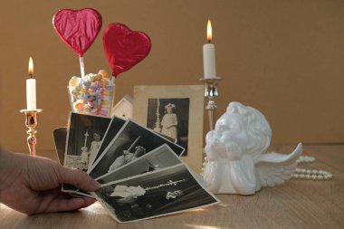 Kadın elinde bir yığın klasik fotoğraf, aşk tarzında romantik bir hayat, cam vazodaki kırmızı kalpler, renkli şekerler, yanan mumlar, aile ağacı konsepti, soy ağacı, çocukluk anıları.