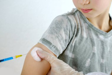 Doktorun elindeki yakın çekim şırıngası, eldivenli hemşire 8 yaşındaki çocuğa iğne yapıyor, tıbbi konsept, Coronavirus covid-19 virüsüne karşı aşı, kas içi vitaminler, insülin
