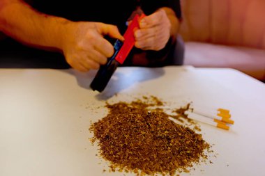 Erkek ellerinin manuel sigara sarma makinesi, sigara için evde yapılan bir yığın kesik tütün, pahalı tütün ürünleri konsepti, kötü bağımlılık, nikotin bağımlılığı, seçici odaklanma