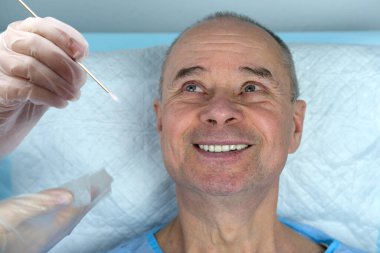 Olgun bir adam, doktorun elleri tükürük örneği, DNA için biyolojik materyal, patoloji, virüsler, ağzından CV19, tıbbi muayene, genetik araştırma, babalık testi...