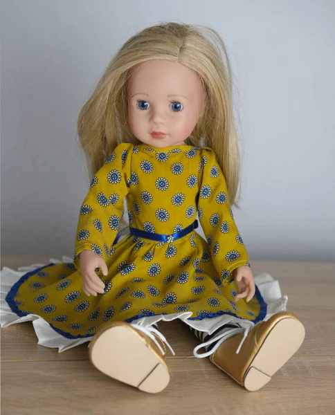 doll with long blond hair in smart clothes, in ayellow dress and boots, concept children\'s toy, doll fashion, hobby, for girls, happy childhood