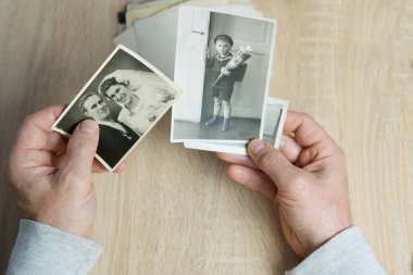 Yakın plan erkek, 1940-1950 yılları arasında çekilmiş eski vintage fotoğraflarını tutuyor. Aile ağacı, soy ağacı, çocukluk anıları, atalarımızın hafızası.