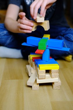 çocuk, çocuk renkli ahşap küplerle oynar, evler ve roketler yapar, yaratıcılığın gelişimi, iyi motor beceriler, sabır ve azim kavramı