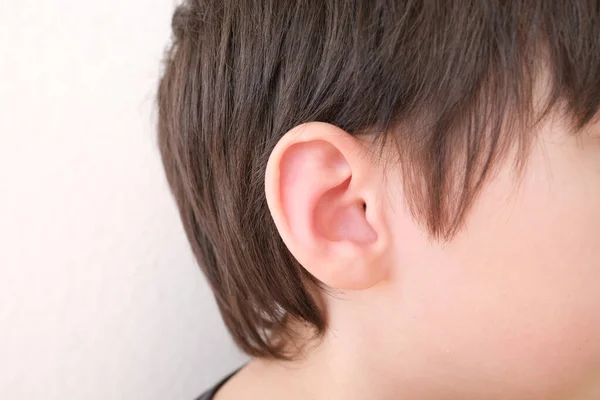 part of child\'s face in profile, a boy of 10 years old touches sore ear, concept of hearing organs health, happy childhood, prevention of otitis media and hearing loss, World Hearing Day