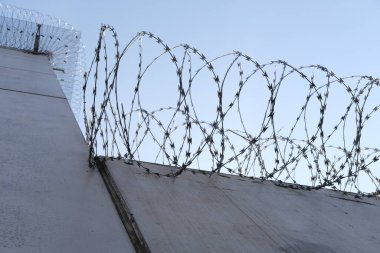 Dikenli teller, yüksek beton çitler, dikenli teller, suçlulara verilen cezaların infazı için bina, konsept hapishane, güvenlik bölgesi, esaretin sembolü, umutsuzluğun esareti.