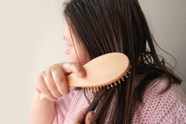 close-up of mature adult woman brushing her hair, combing dirty greasy hair with a wooden massage brush. Woman serious hair loss problem for health care shampoo, beauty product concept, haircut care