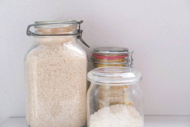 Kapaklı cam kavanozlarda çiğ beyaz ve esmer pirinç yağmurlu günler için stratejik gıda stokları, yemek malzemeleri, ekolojik ambalaj, haşere kontrolü.