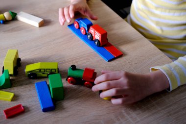 Çocukların ellerinde renkli tahta küpler, dominolar, çocuk 7-9 yaşları ev yapar, araba yuvarlar, inşaat konsepti, yaratıcılığın gelişimi, motor becerileri, sabır.